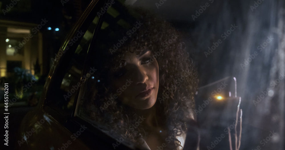 Beautiful Afro American woman tourist traveling in a taxi and rewritten with your friends on your phone at night. Passenger Girl looking at cellphone at night in the back seat of a car.