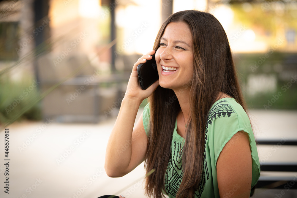 Beautiful Pretty Young Brunette Woman Talking On Phone Cell Phone Outside on at Mall Café with Natural Soft Daylight Beautiful Pretty Young Brunette Woman Talking On Phone Cell Phone Outside on at Mall Café with Natural Soft Daylight