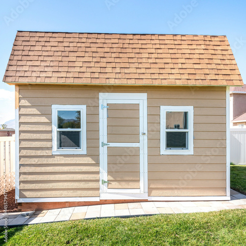 Square frame Shed at a backyard with roof shingles and vinyl wall siding