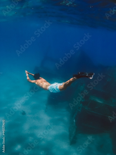 Boy snorkels next to a ship wreck submerged in the ocean