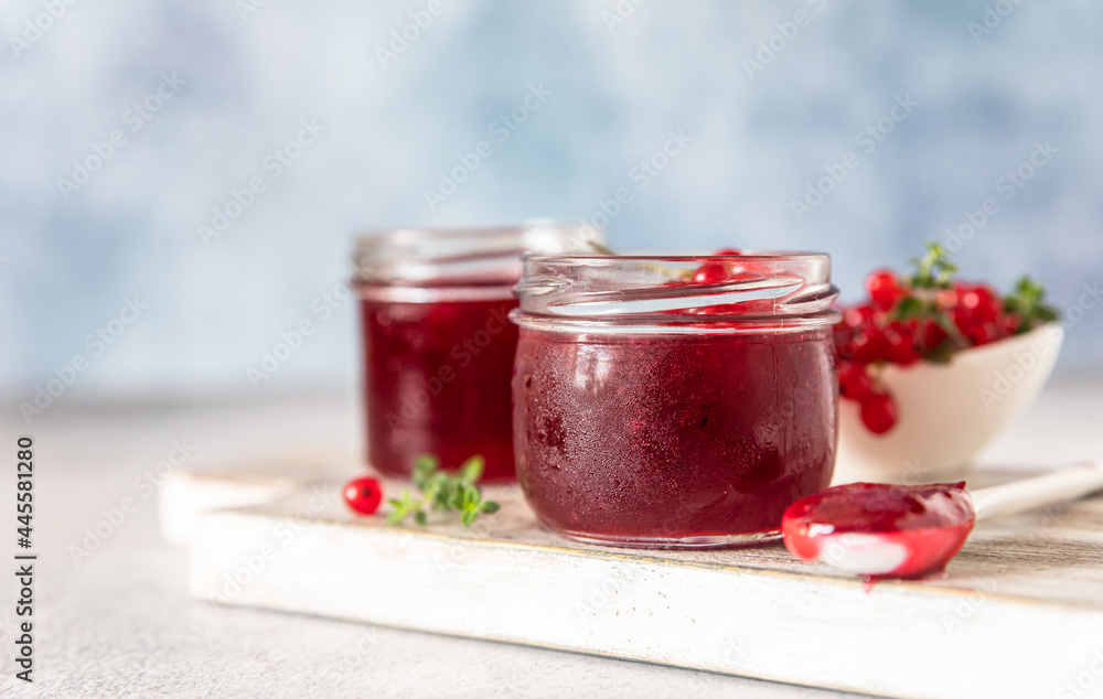 Homemade red currant jam or jelly in glass jars and red currants fresh berries on wooden cutting board. Homemade red currant jam or jelly in glass jars and red currants fresh berries on wooden cutting board.