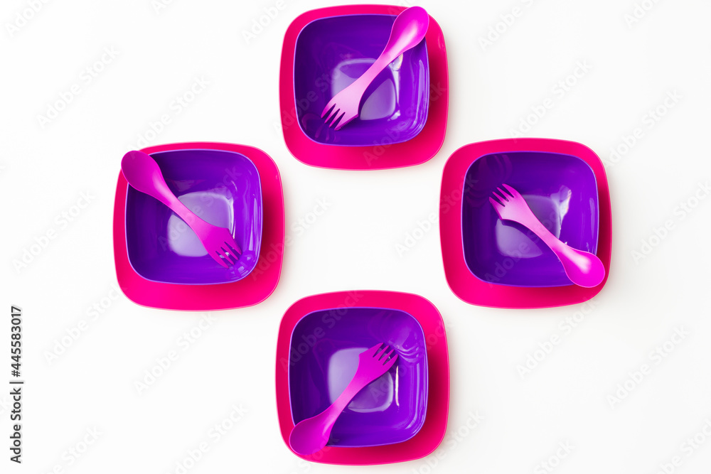 Purple plastic plates and forks with a spoon on a bluish background Purple plastic plates and forks with a spoon on a bluish background