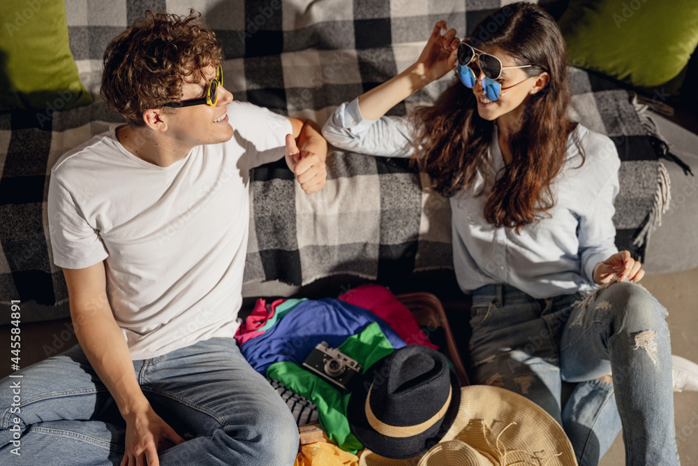 Obraz premium Young family couple preparing to summer vacation sitting at home, indoors. Taking right decision. Look happy, delighted.
