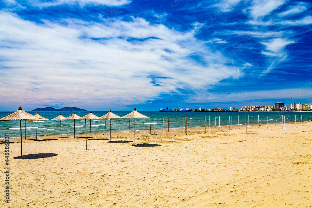 Empty beach with reed beach umbrellas, nobody on the beach. Beautiful blue sky, hot weather. Beach with no travellers and tourists. Cancellations due to coronavirus covid-19. Quarantine.