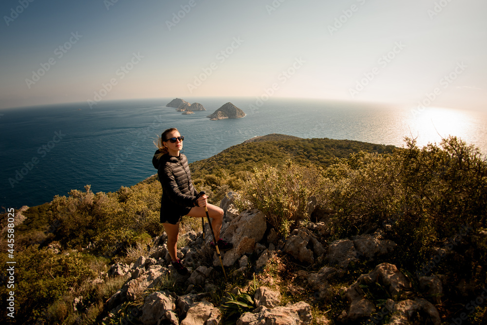 panoramic view of beautiful woman with hiking poles at seascape background