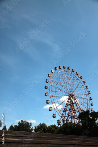 observation wheel in urban park against blue sky