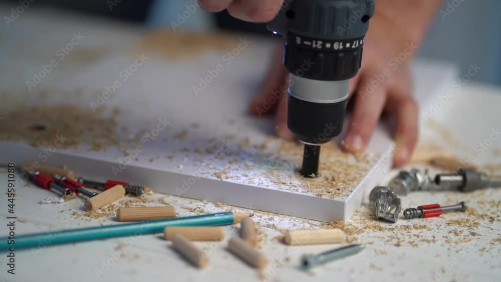 Man doing hole in furniture door using electric tool at workshop, close up Man doing hole in furniture door using electric tool at workshop, close up