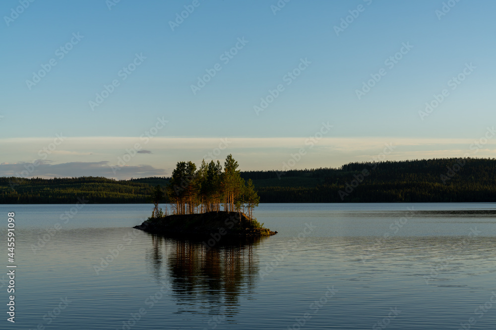 idyllic lake landscape with a small island with trees under a cloudless blue sky