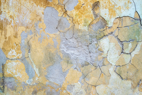 damaged weathered multicolored coating of paint of concrete building wall with many patches