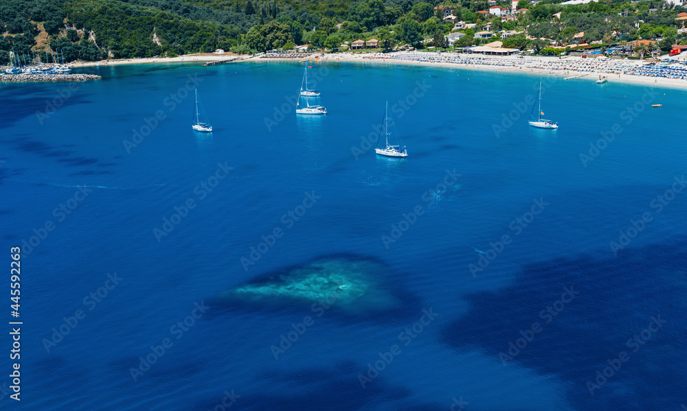 Mediterranean deep blue sea bay with heart shaped shallow water, sailing yachts and sandy coastline