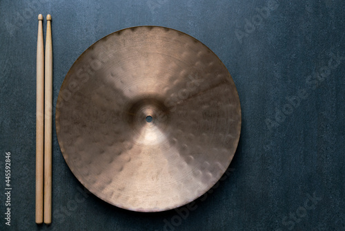 Drum stick and crash cymbal on black table background, top view, music concept