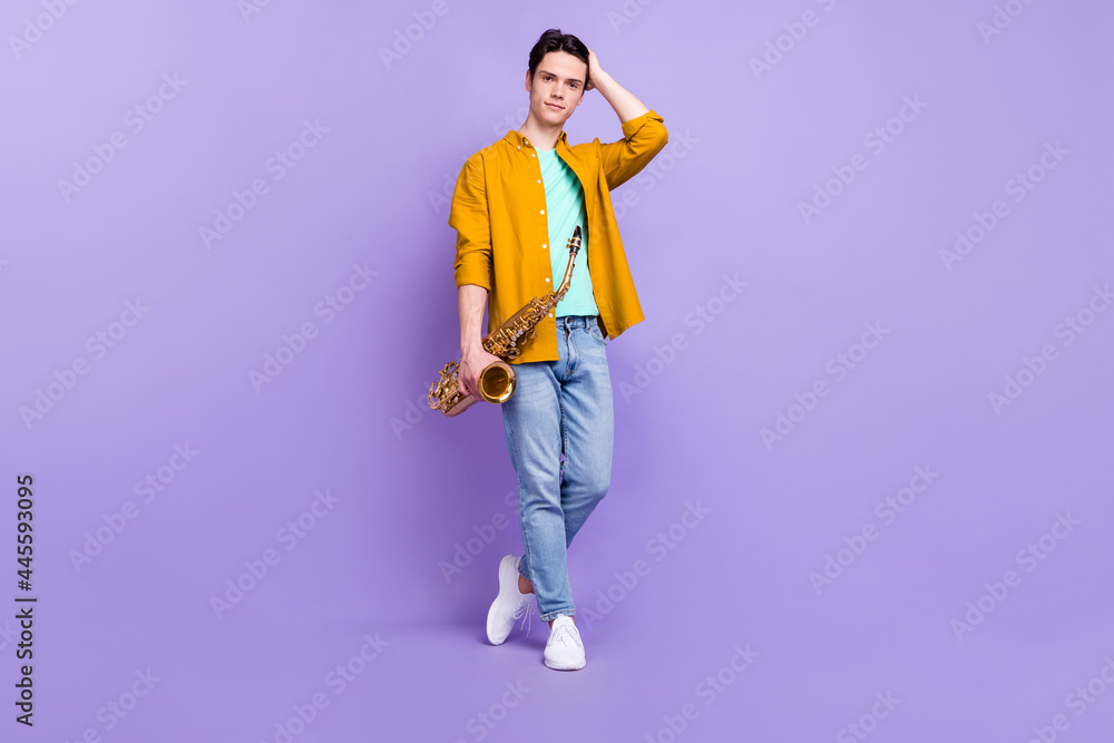 Full size photo of nice brunet millennial guy play sax wear brown shirt jeans isolated on violet color background