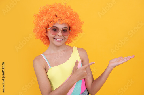 happy kid in sunglasses pointing finger on yellow background copy space, promotion.