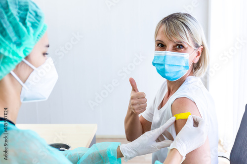 woman wearing mask getting vaccinated concept of coronavirus vaccination mask grown woman approved for covid-19 vaccination at the hospital. Female doctor immunizes against the virus,  medical plaster