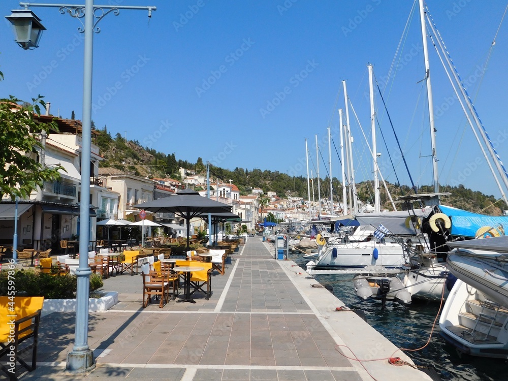 A seaside street with restaurants, traditional houses and boats, in the island’s town, at Poros, Greece