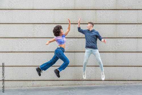 multiethnic couple jumping at the same time high-fiving