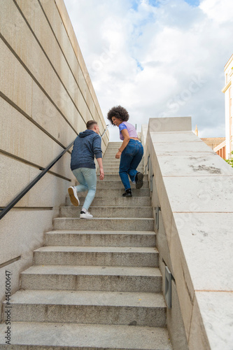 young multiracial couple climbing stairs having fun and laughing 20s © luisrojasstock