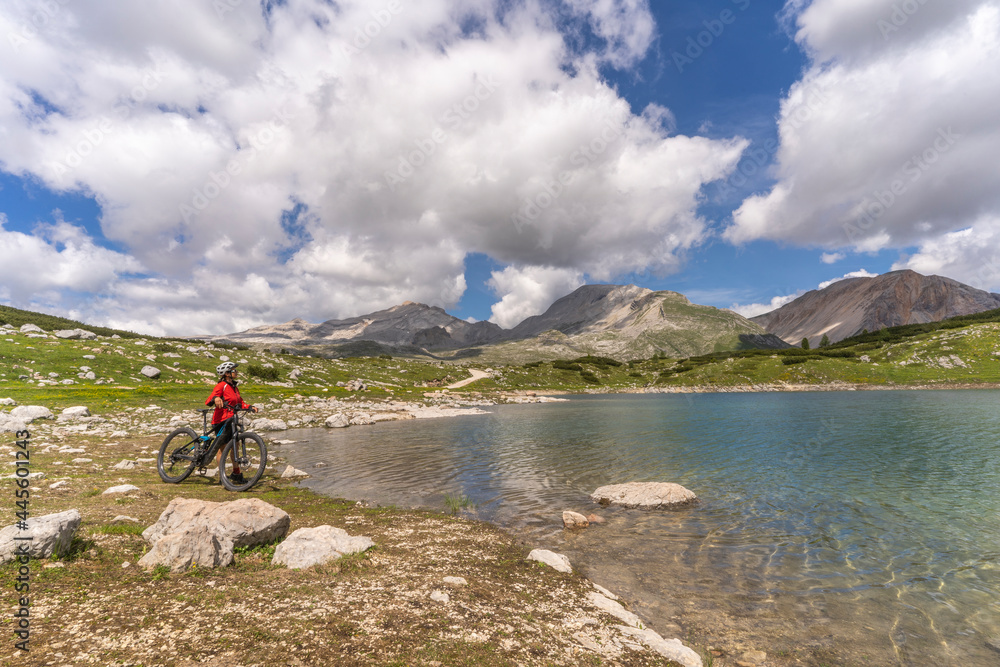 pretty active senior woman riding her electric mountain bike at Lago de in the Fanes high Valley, part of Fanes-Sennes-Braies nature park in the Alta Badia Dolomites,  South Tirol and Trentino, Italy
