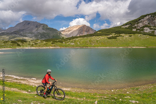 pretty active senior woman riding her electric mountain bike at Lago de in the Fanes high Valley, part of Fanes-Sennes-Braies nature park in the Alta Badia Dolomites, South Tirol and Trentino, Italy 