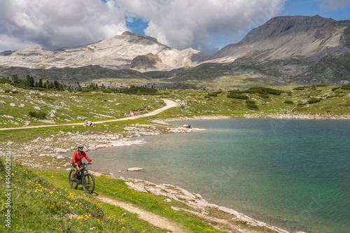 pretty active senior woman riding her electric mountain bike at Lago de in the Fanes high Valley, part of Fanes-Sennes-Braies nature park in the Alta Badia Dolomites, South Tirol and Trentino, Italy 