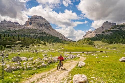 pretty active senior woman riding her electric mountain bike in the Fanes high Valley, part of Fanes-Sennes-Braies nature park in the Alta Badia Dolomites, South Tirol and Trentino, Italy 