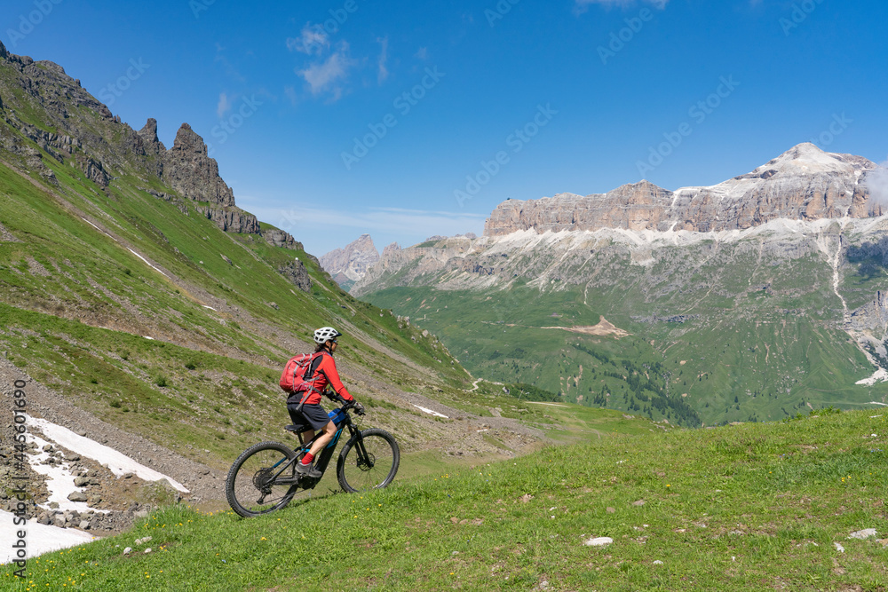 Fototapeta premium pretty active senior woman riding the famous Sella Ronda mountain bike Trail in Sella mountain group, Dolomites of Selva Wolkenstein, Val Gardena, South Tirol and Trentino, Italy