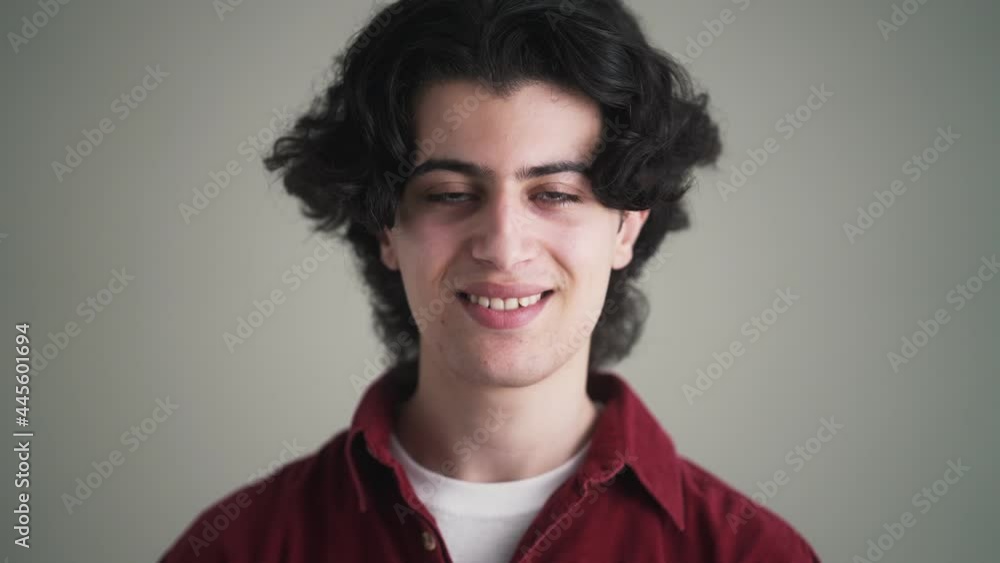 A brunette man in a red shirt is nodding standing isolated over grey background in the studio A brunette man in a red shirt is nodding standing isolated over grey background in the studio