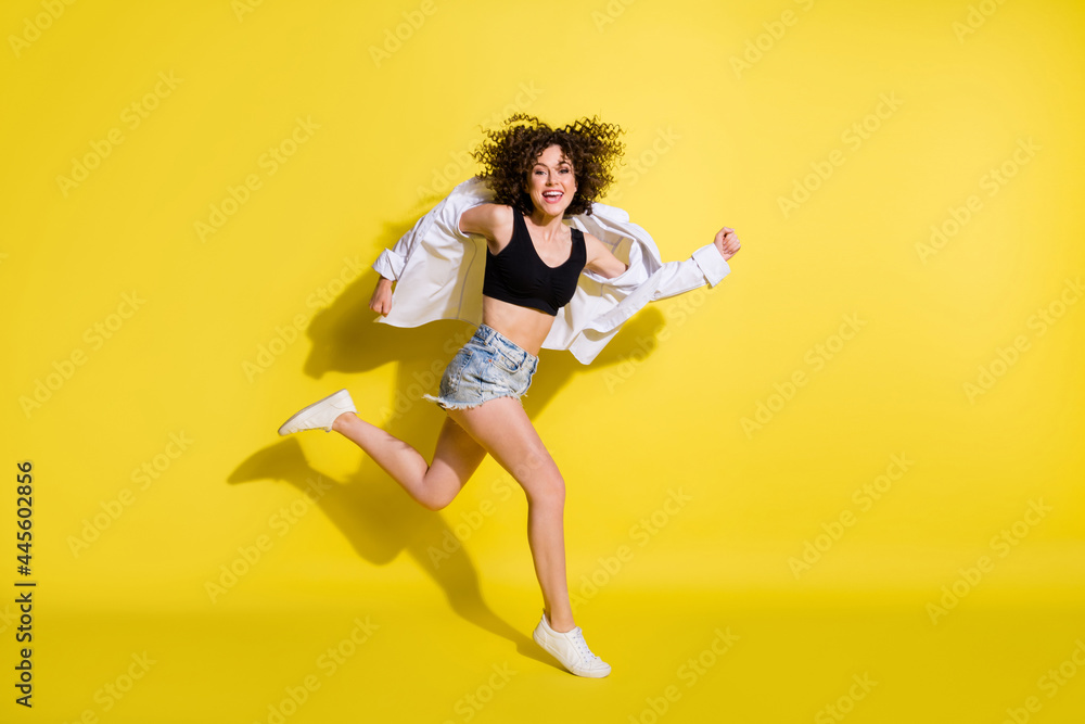 Photo of pretty shiny young lady wear black top smiling jumping running fast isolated yellow color background Photo of pretty shiny young lady wear black top smiling jumping running fast isolated yellow color background