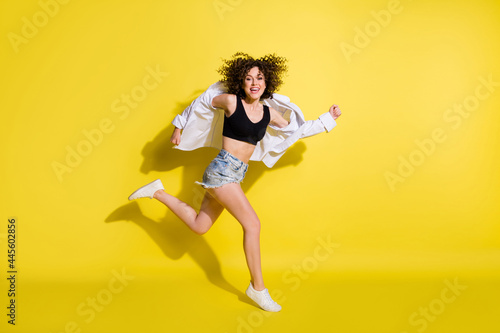 Fototapeta Naklejka Na Ścianę i Meble -  Photo of pretty shiny young lady wear black top smiling jumping running fast isolated yellow color background