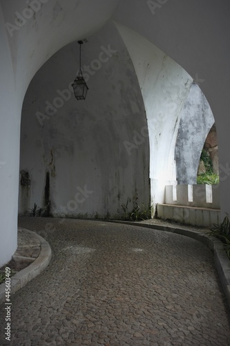 Sintra impression: smooth turn into the old arch of the white corridor with lantern inside the fairytale entrance great palace of Pena. Porgugal photo