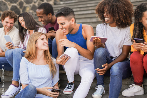 Group of young multiracial people having fun in the city with mobile phone - Millennial generation friends having social moment outdoor