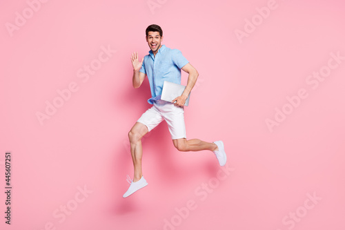 Full length body size photo man waving hand jumping up with laptop isolated pastel pink color background