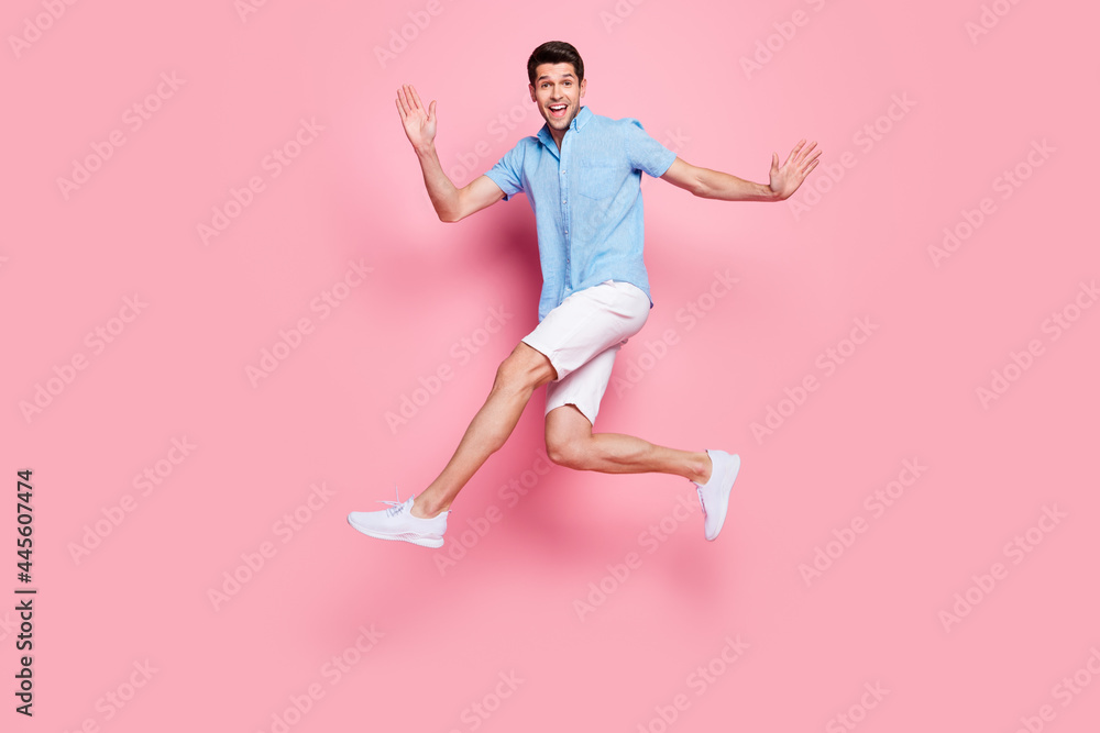 Photo of careless athletic man jump run enjoy summer holiday wear blue shirt shorts shoes isolated on pink color background