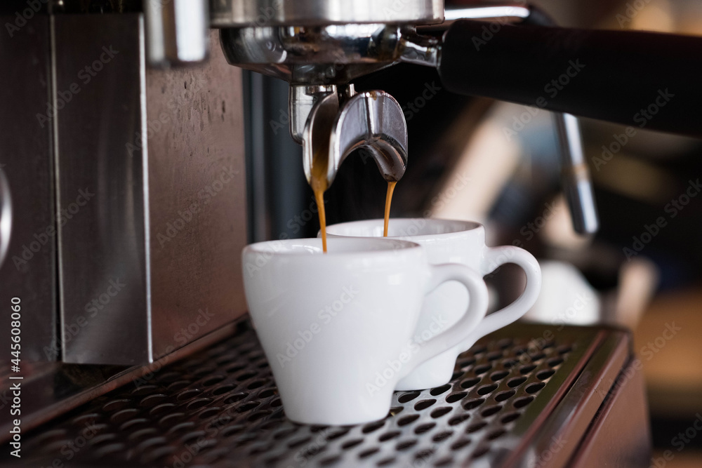 The espresso machine pours two coffees into white cups. The espresso machine pours two coffees into white cups.