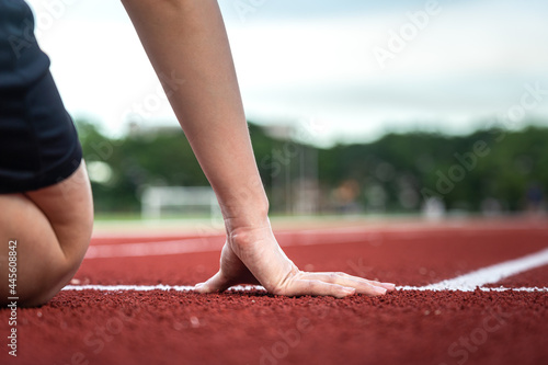 Action of a runner is placing hand on starting position of running racetrack, ready to start. Sport challenge competition abstract photo.  © Nattawit