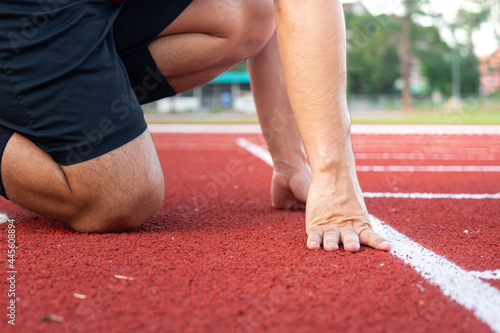 Action of a runner is placing hand on starting position of running racetrack, ready to start. Sport challenge competition abstract photo. 