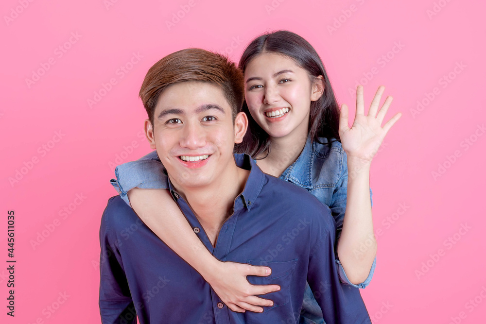 Portrait young man carrying his girlfriend on back and looking camera with smile on pink background , Teenager couple concept Portrait young man carrying his girlfriend on back and looking camera with smile on pink background , Teenager couple concept