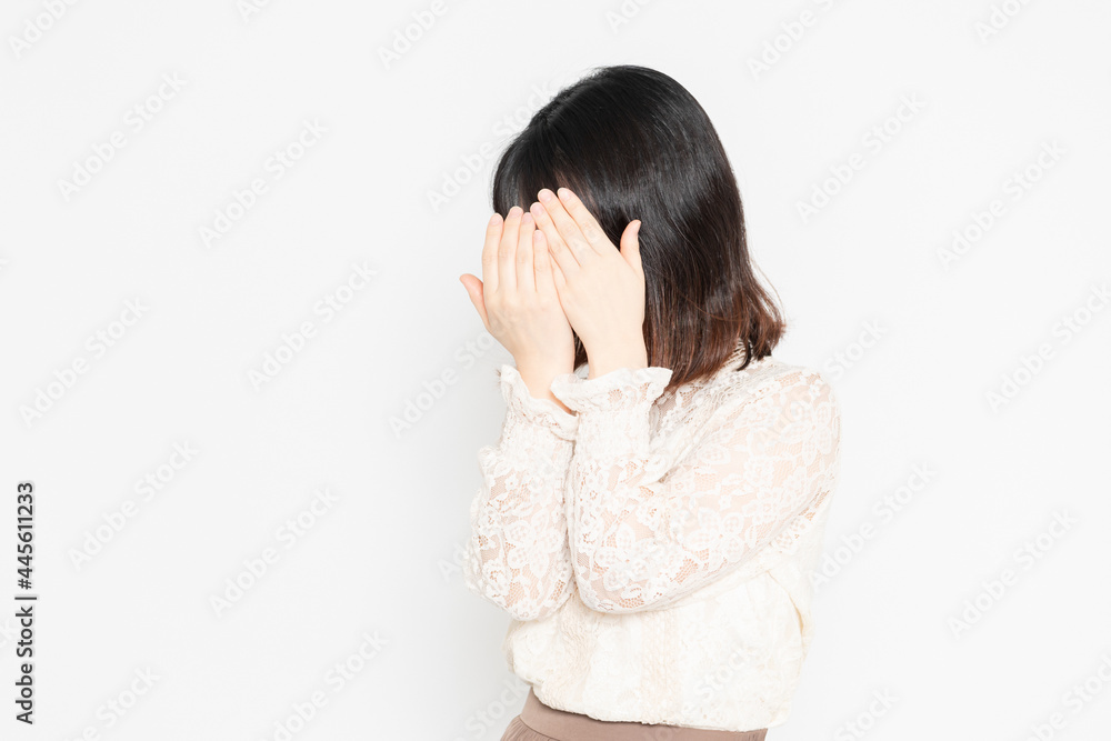 白背景の前に立って、顔を隠す、レースのブラウスを着た若い女性 白背景の前に立って、顔を隠す、レースのブラウスを着た若い女性