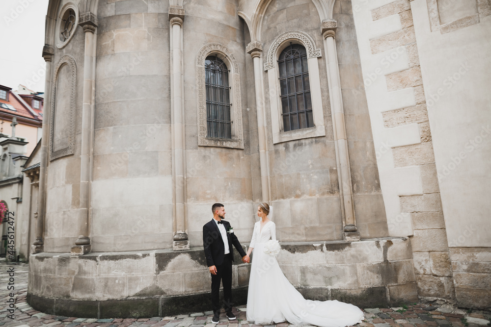 Gorgeous happy couple standing close to each other and looking in eyes at old city background, wedding photo, European city, wedding day in Lviv