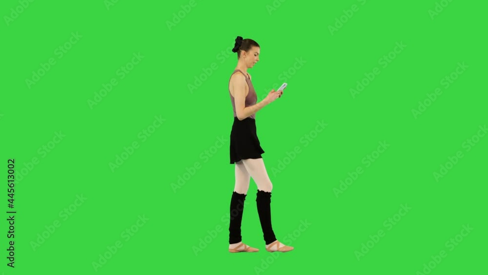 Young ballerina in training clothes walks with mobile phone in hands, typing and scrolling on a Green Screen, Chroma Key. Young ballerina in training clothes walks with mobile phone in hands, typing and scrolling on a Green Screen, Chroma Key.
