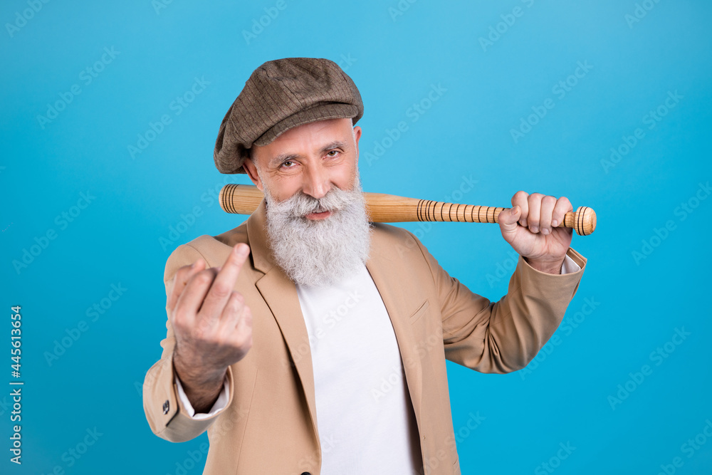Portrait of attractive aggressive grey-haired man holding bet showing middle finger isolated over bright blue color background Portrait of attractive aggressive grey-haired man holding bet showing middle finger isolated over bright blue color background