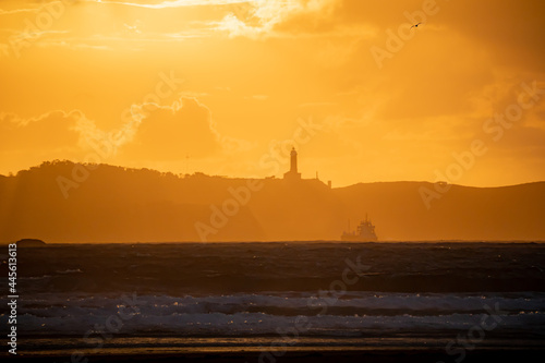Fototapeta Naklejka Na Ścianę i Meble -  Sunset on the beach of Loredo in the municipality of Somo in the province of Santander, with views of the lighthouse and large clouds