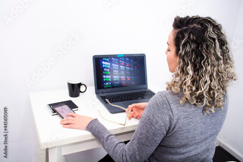 young woman analyzes financial charts and holds her glasses in home office