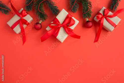 Top view of Christmas gifts with tiew red bow on the red background. Copy space. photo