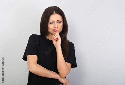 Beautiful serious angry thinking young woman looking down in black t-shirt on empty copy space