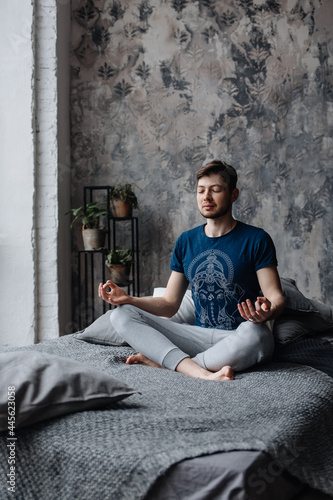 A young man sitting in meditation with his hands folded in a yoga mudra © Kate Chernyshova