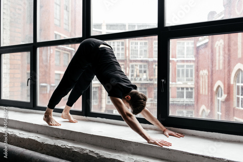 A young man performing yoga asanas and sports exercises to improve the strength and flexibility of the body