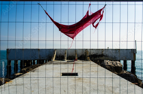 Uno straccio rosso appeso a una grata che chiude l’accesso a un pontile del Ludo di Venezia photo
