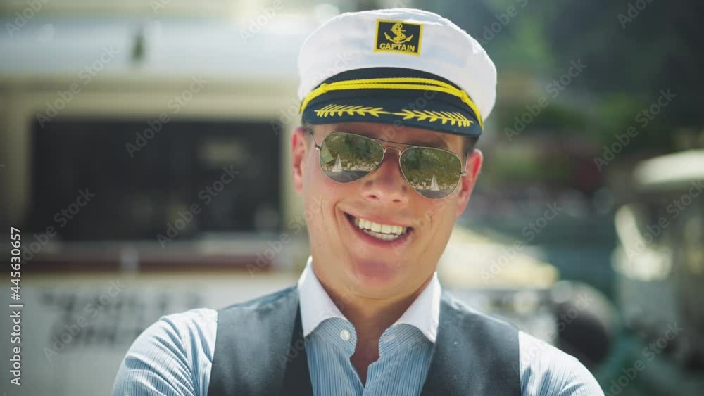Smiling captain standing in marina. Headshot of man wearing sunglasses and sailor captain hat. Summer vacation at sea, sailing and travelling concept. Smiling captain standing in marina. Headshot of man wearing sunglasses and sailor captain hat. Summer vacation at sea, sailing and travelling concept.