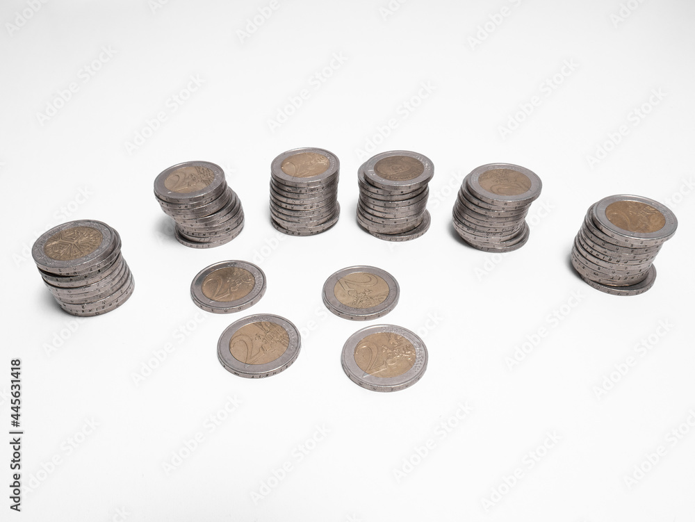 Six columns of two euro coins and four loose coins forming a structure on a white background Six columns of two euro coins and four loose coins forming a structure on a white background